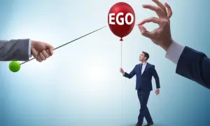 Mężczyzna z balonem "EGO" w ręku, symbolizujący cechy narcyza, zagrożony przez szpilkę.